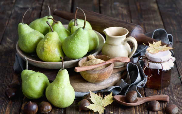 HD still life desktop wallpaper featuring fresh green pears, honey jar, wooden utensils, and autumn leaves on a rustic wooden table, evoking the fall season.