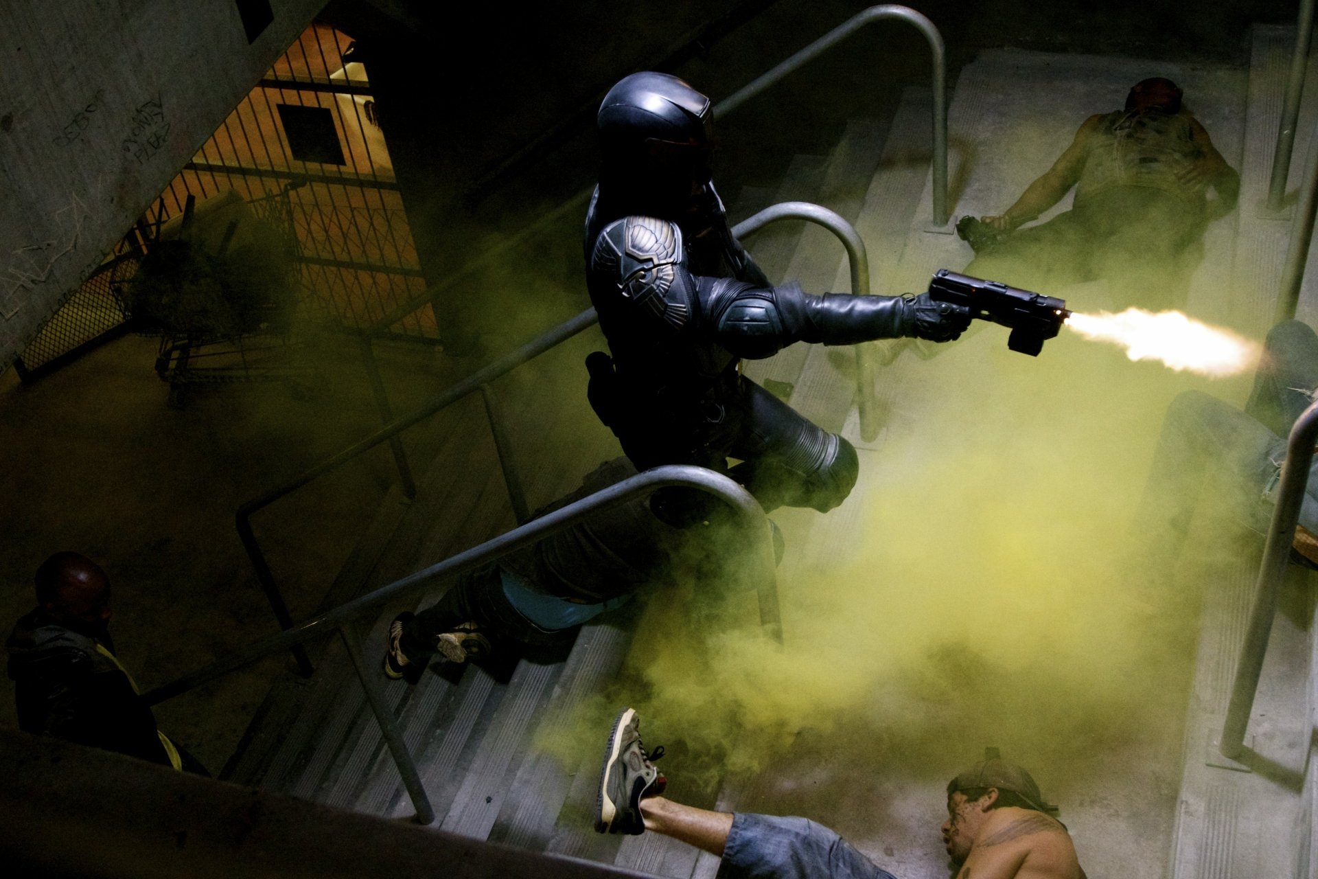 4K Ultra HD desktop wallpaper of Judge Dredd from the movie Dredd, depicted firing a weapon amid smoke on a dimly lit staircase.