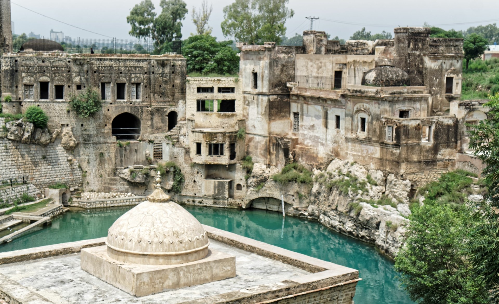 5K Ultra HD desktop wallpaper: Katasraj Temple, Pakistan — ancient religious stone temple and domed shrine reflected in tranquil turquoise water.