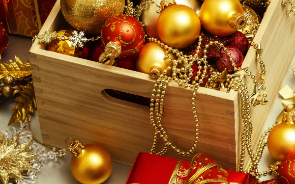 A festive arrangement featuring a wooden box filled with golden and red Christmas ornaments, ribbons, and decorative beads, evoking the holiday spirit. 4K Ultra HD desktop wallpaper.