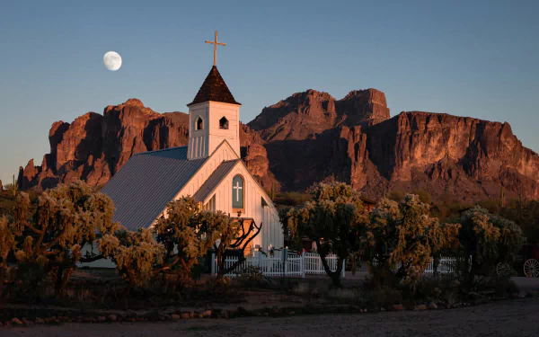 A serene HD desktop wallpaper featuring a small church with a cross, set against a mountain backdrop and a moonlit sky, capturing a peaceful religious scene.