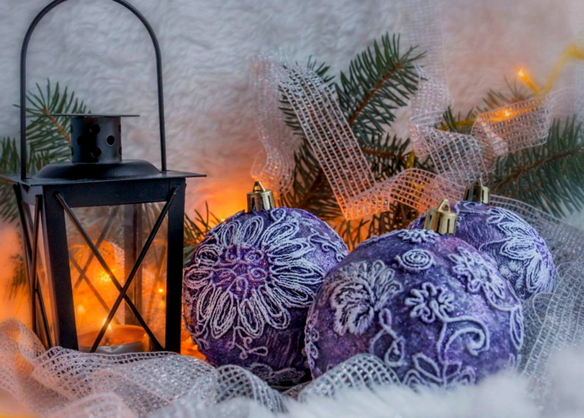 A cozy holiday scene featuring a decorative lantern alongside beautifully patterned purple Christmas ornaments, set against a backdrop of greenery and soft lights, creating a warm festive atmosphere.
