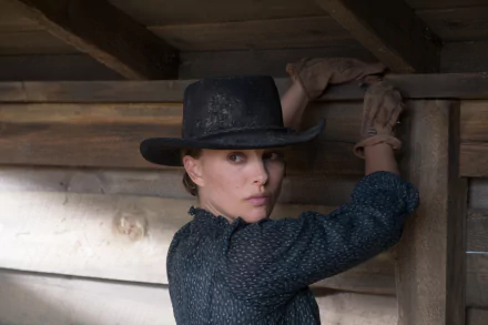 Woman in a cowboy hat and gloves leans against a wooden barn wall — still from the movie Jane Got a Gun; HD PC desktop wallpaper.