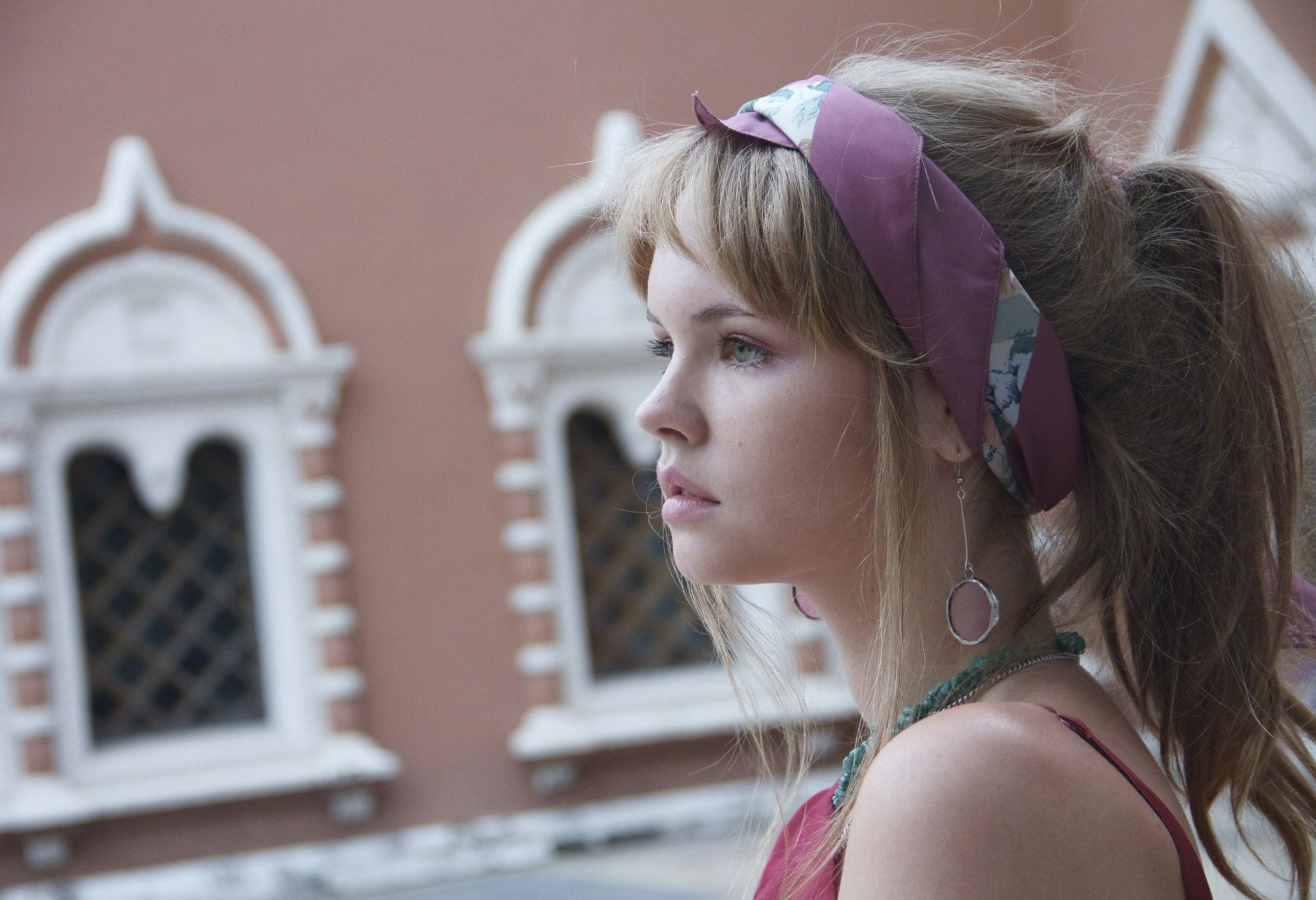 A high-definition desktop wallpaper featuring a woman, identified by the tag as Anastasiya Scheglova, with long hair and a headband, set against a background of architectural details.