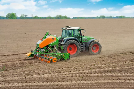 Green Fendt tractor planting in a freshly tilled field, HD PC desktop wallpaper/background showing an agricultural vehicle under a blue sky.