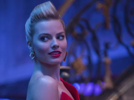 A glamorous blonde actress, featuring bold red lipstick, poses against a vibrant blue background, showcasing Margot Robbie's captivating presence in a movie scene.