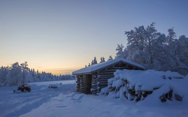 A 4K Ultra HD winter desktop wallpaper showing a man-made wooden cabin covered in snow at sunrise, surrounded by snow-covered trees and landscape.