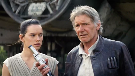 Harrison Ford as Han Solo and Daisy Ridley as Rey stand together in a scene from Star Wars Episode VII: The Force Awakens, featuring a dramatic backdrop of the Millennium Falcon.