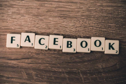 A close-up of Scrabble tiles spelling FACEBOOK on a wooden surface, showcasing a blend of technology and social media themes in this HD desktop wallpaper.