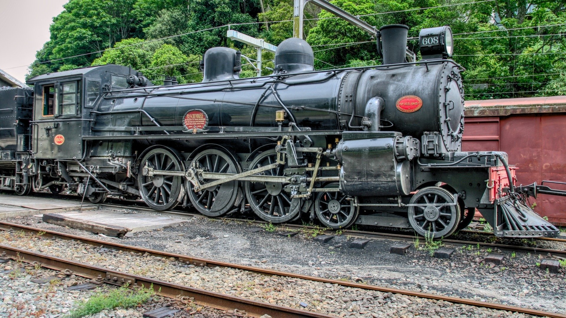 HD PC desktop wallpaper showing a black steam locomotive (train/vehicle) on rails, detailed boiler, wheels and surrounding greenery.
