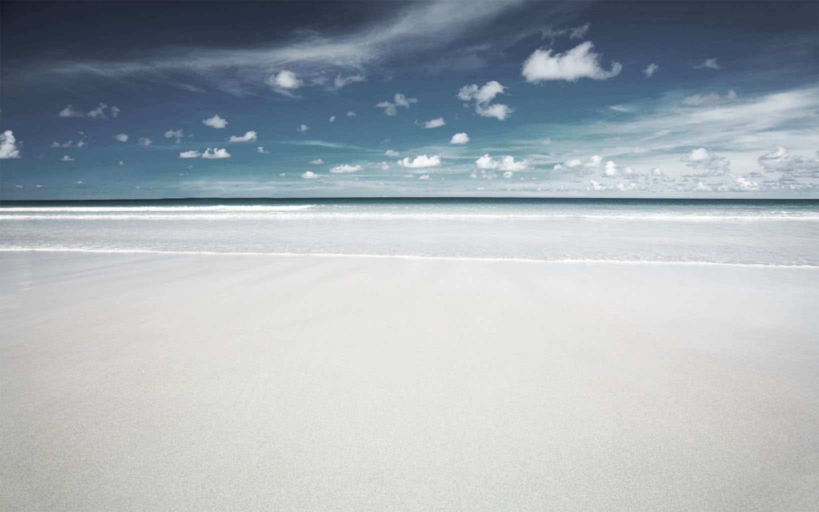 HD PC desktop wallpaper featuring a serene nature scene of a calm beach with smooth sand, gentle waves, and a cloudy blue sky.