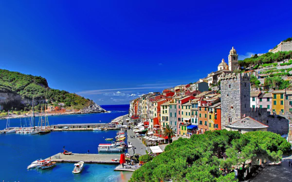 Scenic HD wallpaper of Porto Venere, Italy featuring a vibrant coastal town, boats docked in the harbor, and clear blue skies along the picturesque coastline.