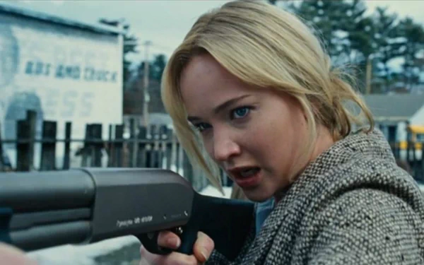 HD desktop wallpaper still from Joy (2015): a determined woman in a coat leans from a car, aiming a shotgun with an intense, focused expression.