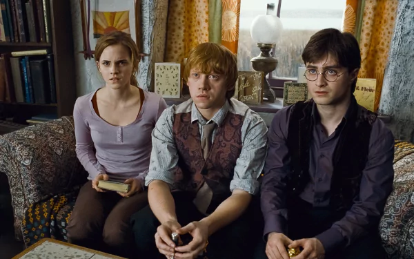 A high-definition wallpaper featuring Ron Weasley, Hermione Granger, and Harry Potter from Harry Potter and the Deathly Hallows: Part 1, sitting together in a cozy setting.