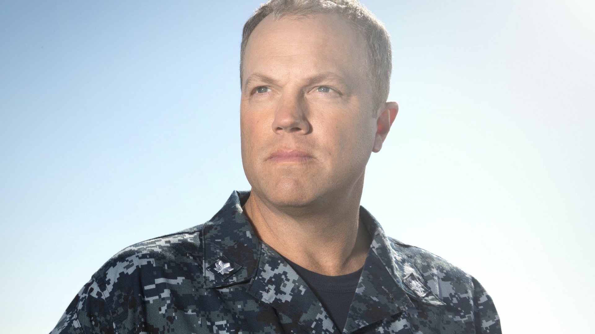 2K Quad HD PC desktop wallpaper for TV show The Last Ship — stern naval officer in digital camouflage uniform gazing toward a pale sky background.