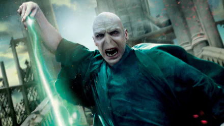 HD PC desktop wallpaper of Lord Voldemort from the movie Harry Potter and the Deathly Hallows: Part 2, screaming as he unleashes a green spell amid crumbling castle battlements.