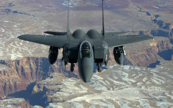 A McDonnell Douglas F-15 Eagle flies above dramatic mountainous terrain, showcasing its sleek design in this HD PC desktop wallpaper and background.