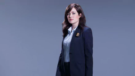 HD PC desktop wallpaper of a female character from the TV show The Blacklist, standing in a navy blazer against a muted blue-gray background.