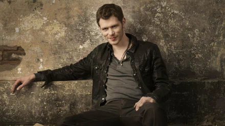 A still from the TV show *The Originals*, featuring a male character in a leather jacket against a textured wall, showcasing a confident and casual vibe. HD wallpaper and background.