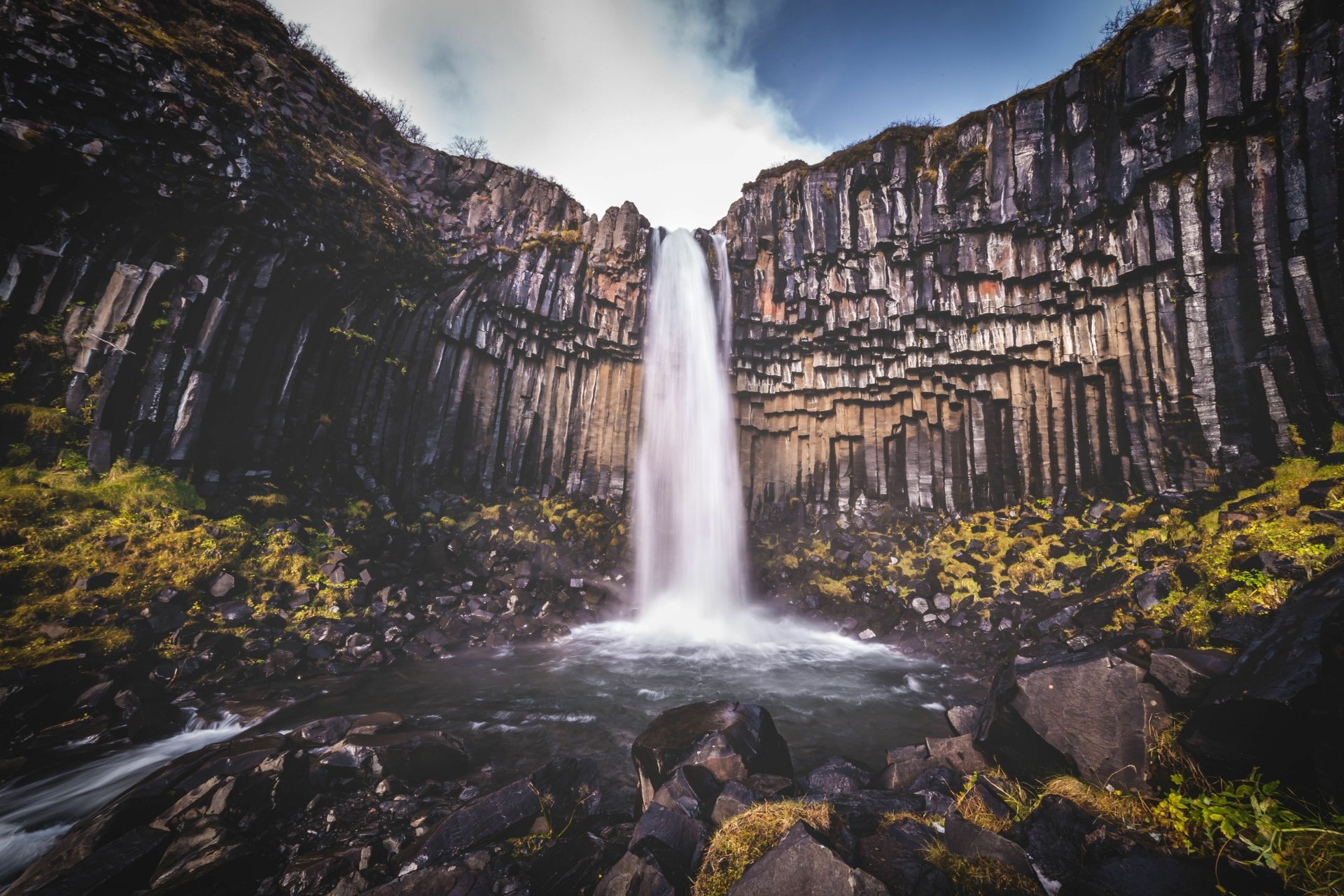 Svartifoss waterfall plunging between hexagonal basalt columns over mossy rocks — 4K Ultra HD nature scene, PC desktop wallpaper and background.