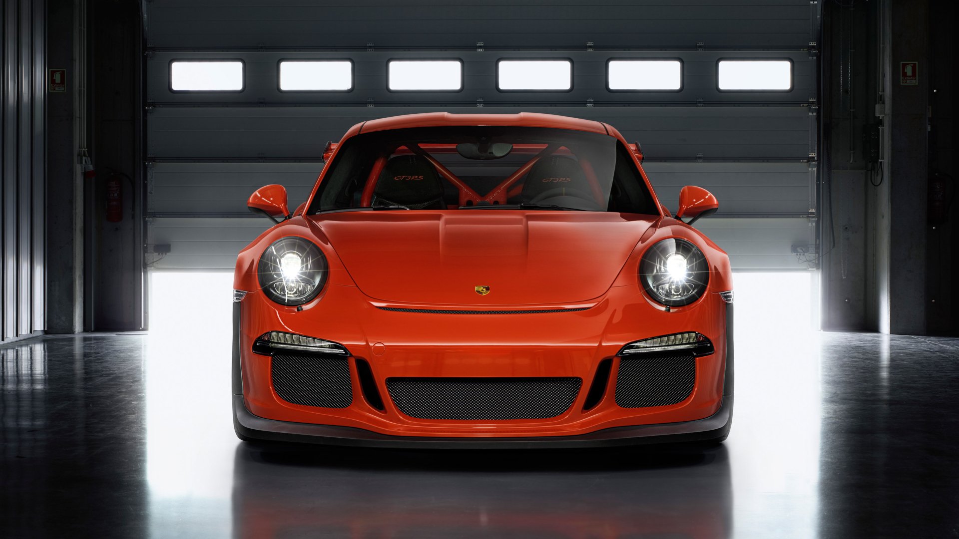Front view of an orange Porsche 911 GT3 RS sports car in a garage — 2K Quad HD PC desktop wallpaper/background featuring a Porsche 911 GT3 vehicle.