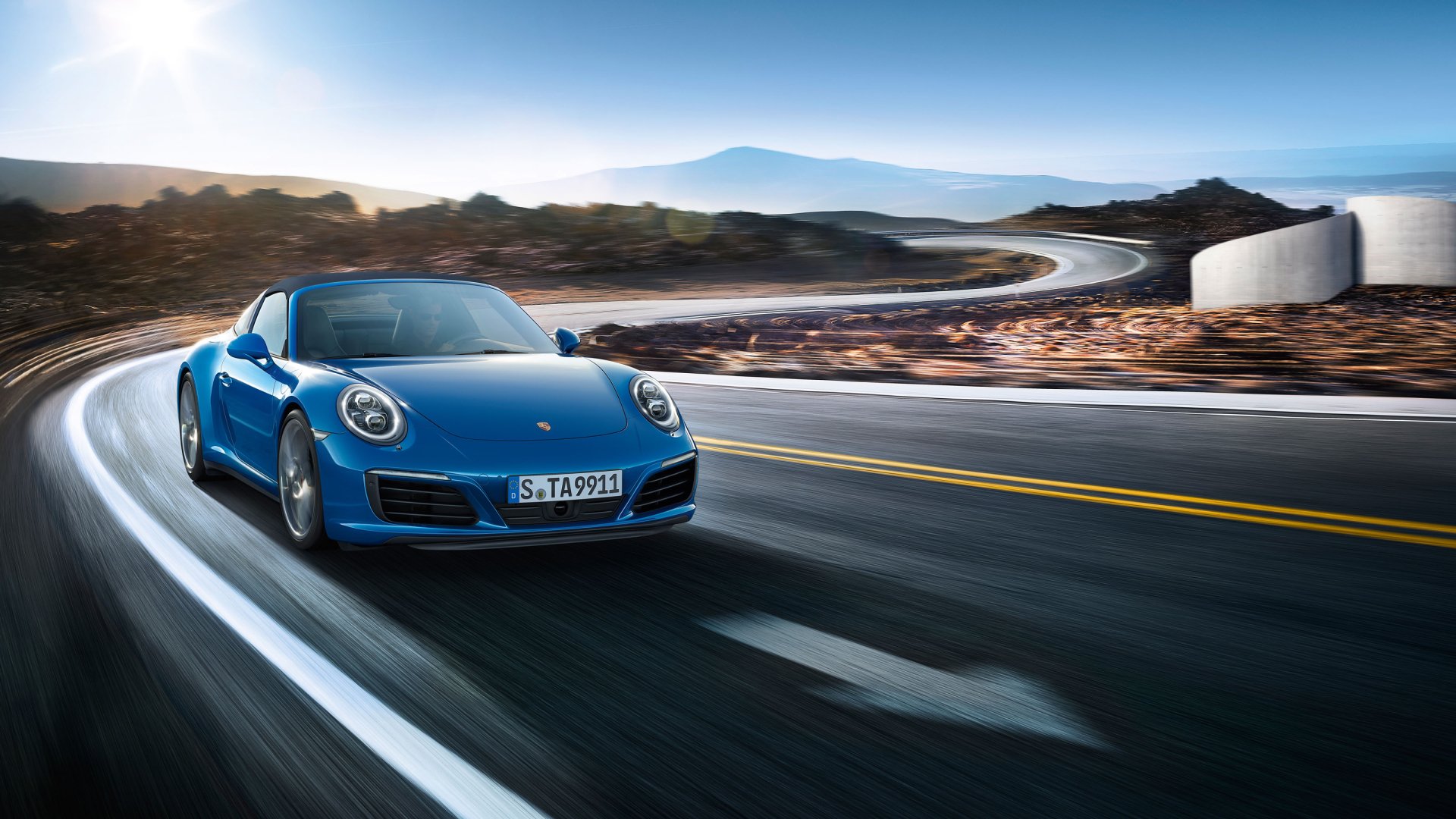 Blue Porsche 911 Targa car on a coastal winding road at sunrise — 2K Quad HD PC desktop wallpaper of the Porsche 911 sports vehicle.