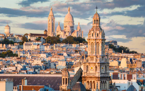 Cityscape of Paris, France featuring the Sacré-Cœur Basilica and surrounding monuments under a partly cloudy sky, captured in HD for a vibrant desktop wallpaper.