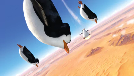 HD PC desktop wallpaper featuring animated penguins from the movie Penguins of Madagascar soaring above a desert landscape.