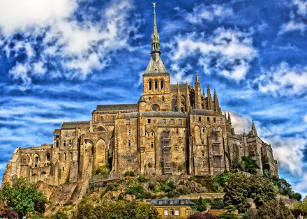 A stunning view of Mont Saint-Michel, featuring its medieval architecture and religious significance, against a dramatic sky. A captivating wallpaper showcasing France's rich history.