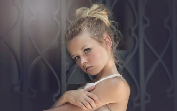 A blonde little girl poses thoughtfully against an ornate background. This captivating photograph is a stunning 4K Ultra HD wallpaper, showcasing the innocence of childhood.
