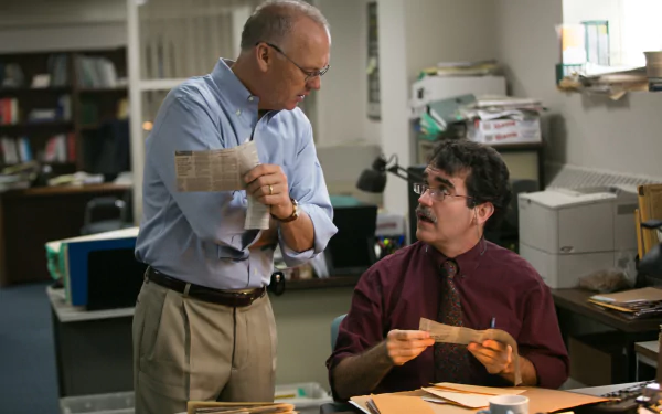 2K Quad HD desktop wallpaper: newsroom scene from Spotlight (2015) showing two reporters reviewing clippings and documents at a cluttered desk.