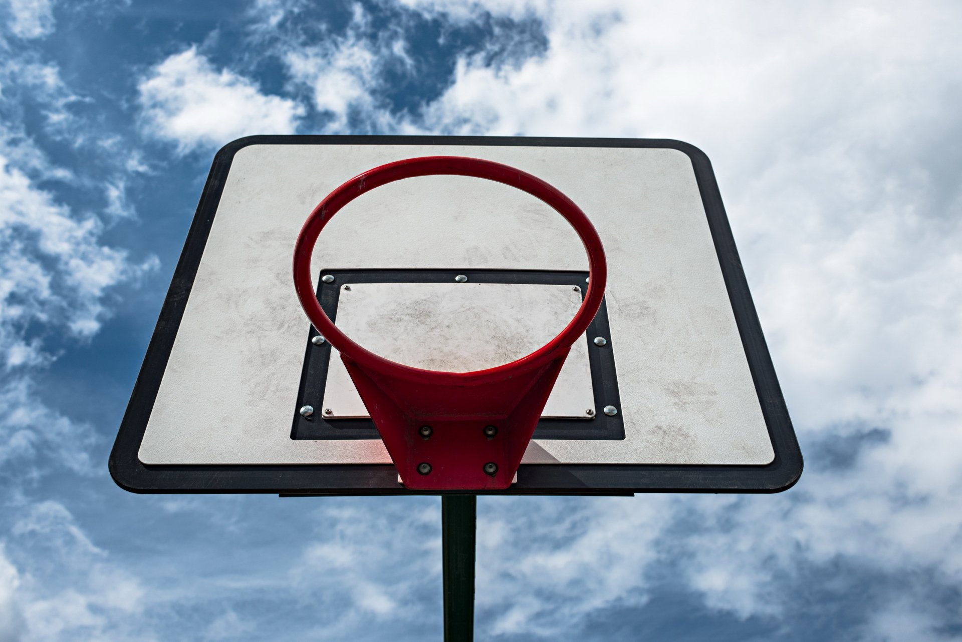 A vibrant basketball hoop stands against a backdrop of blue skies and fluffy clouds, capturing the essence of outdoor sports in a stunning HD desktop wallpaper.
