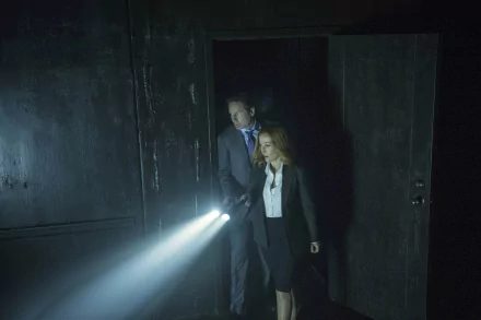Two investigators in business attire sweep a dark room with flashlight beams; moody 4K Ultra HD TV-series desktop wallpaper evoking a 1990s paranormal drama.
