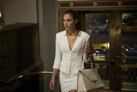 Diana Prince, portrayed by Gal Gadot, steps confidently through a grand entrance in a stylish white suit, capturing the essence of Wonder Woman in a scene from *Batman V Superman: Dawn Of Justice*.