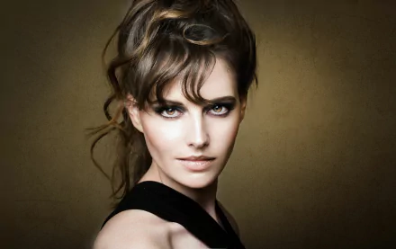 HD desktop wallpaper featuring a brunette woman model with striking brown eyes against a warm, muted background.