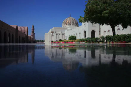 HD desktop wallpaper: Sultan Qaboos Grand Mosque in Muscat, Oman, white dome and minaret reflected in a tranquil pool, framed by gardens and clear blue sky, striking religious architecture.