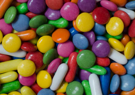 A vibrant assortment of Smarties candies in various colors sprawls across the image, creating a colorful and inviting backdrop for any desktop wallpaper.