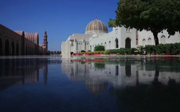 HD desktop wallpaper: Sultan Qaboos Grand Mosque in Muscat, Oman, white dome and minaret reflected in a tranquil pool, framed by gardens and clear blue sky, striking religious architecture.