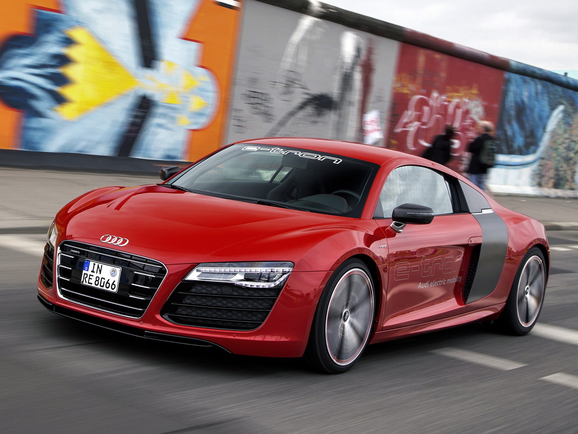 A striking Audi R8 in vibrant red, showcasing its sleek design against a colorful urban backdrop. This HD wallpaper captures the essence of luxury and performance in a supercar.