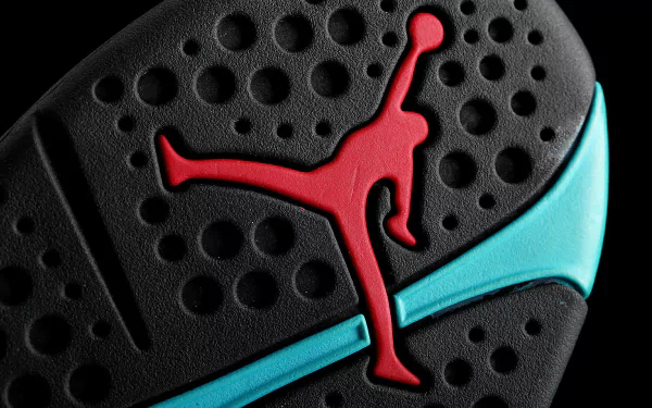 Close-up HD wallpaper of the Jordan logo, featuring a red silhouette of Michael Jordan in a jumping pose on a textured black and teal background.