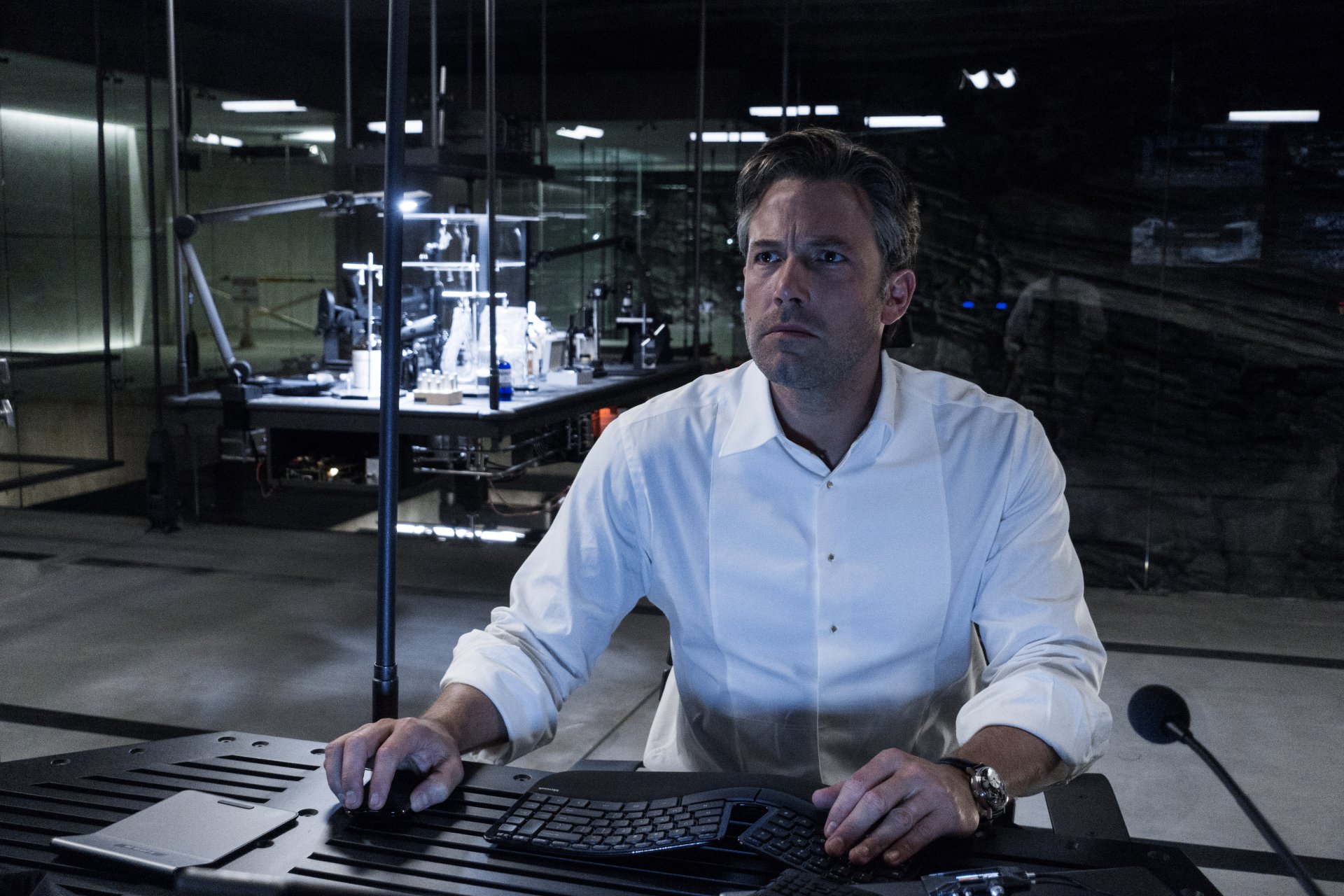 Bruce Wayne, portrayed by Ben Affleck in Batman V Superman: Dawn of Justice, sits at a computer in a dark, high-tech setting. 4K Ultra HD movie wallpaper.
