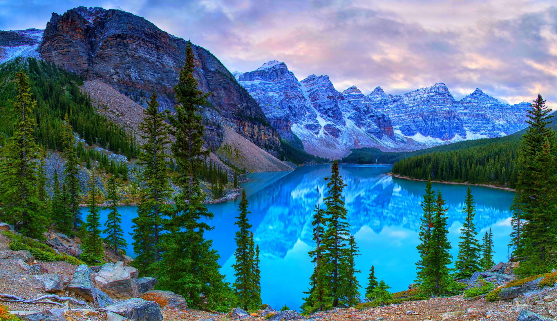 Stunning 4K Ultra HD view of Moraine Lake in Banff National Park, Canada, featuring vibrant turquoise water, evergreen trees, and rugged mountain peaks under a colorful sky.
