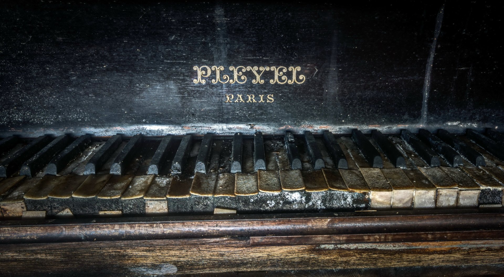 Close-up of an old, weathered piano keyboard with chipped keys and faded brand text, captured in 4K Ultra HD as a detailed PC desktop wallpaper background.