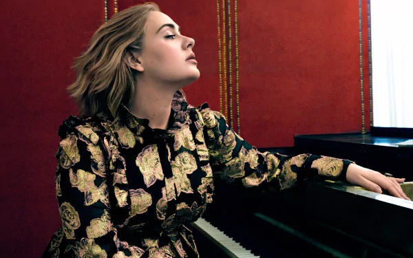 HD desktop wallpaper of English singer Adele with blonde hair, sitting at a piano against a red backdrop, embodying music and elegance.