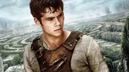 Dylan O'Brien in a dramatic scene from *The Maze Runner*, featuring a close-up of his determined expression against a backdrop of a mysterious maze. High-definition desktop wallpaper.