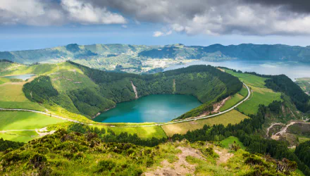 A stunning view of a lake surrounded by lush greenery and hills in the Azores, Portugal, captured in vibrant detail, showcasing the region's natural beauty.