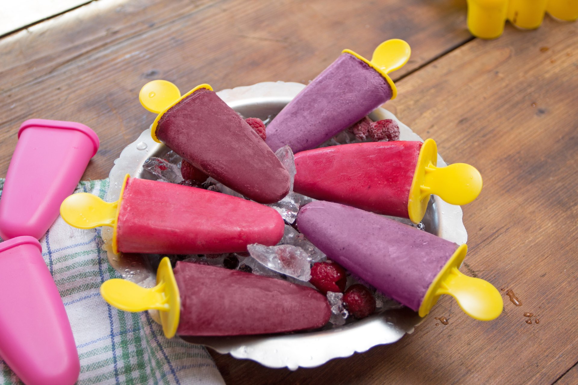 Raspberry and berry ice cream pops on crushed ice, yellow-handled molds arranged on a plate — summer food wallpaper with 5K Ultra HD detail and ice climbing textures.