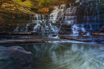 Albion Falls in Canada cascades over layered rock formations, surrounded by lush greenery, captured in stunning 4K Ultra HD detail as a serene nature scene.