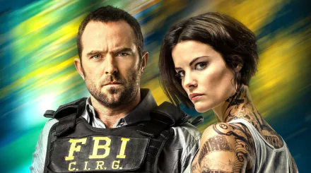 HD PC desktop wallpaper featuring Jaimie Alexander and Sullivan Stapleton from the TV show Blindspot, with a dynamic blurred background.