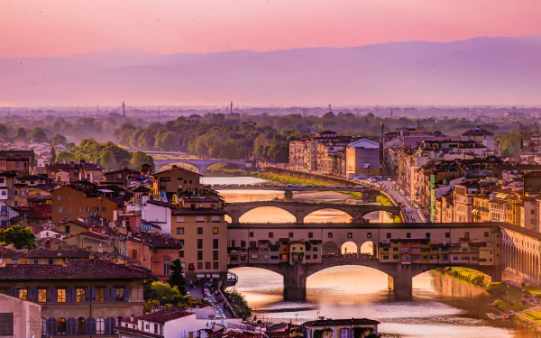Sunset view of Florence, Italy, featuring the Arno River, historic bridges, and cityscape with iconic man-made landmarks.